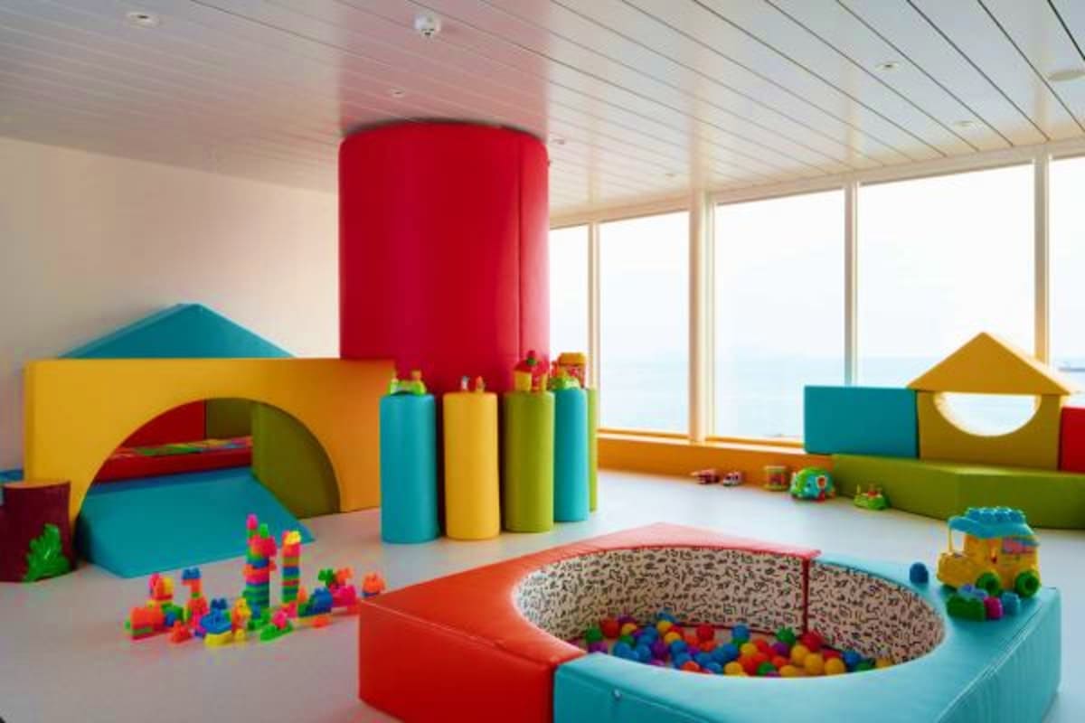 Bright, colorful children's play area with foam structures, building blocks, ball pit, and toys with ocean view windows